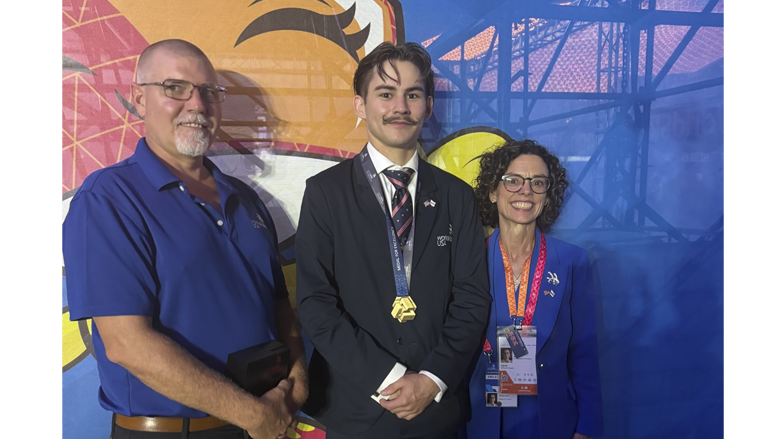 Charles et deux autres personnes posant avec lui portant sa Médaille d'excellence.